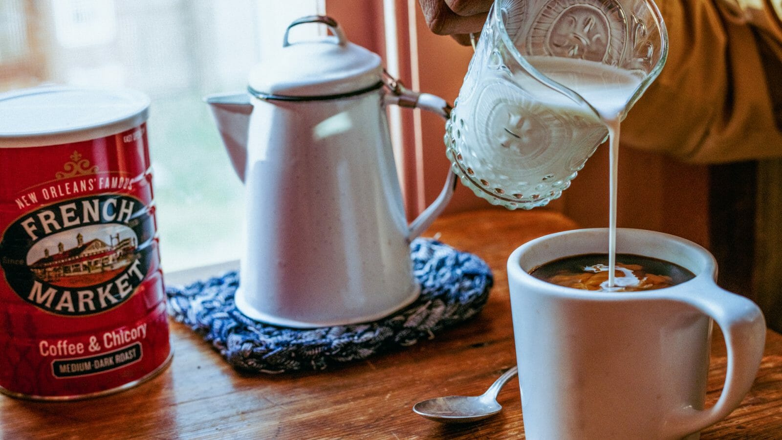 Milk being poured into a white mug of French Market Coffee to make Cafe Au Lait